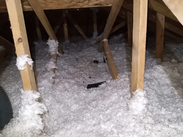 New white blown-in insulation filling the joist bays