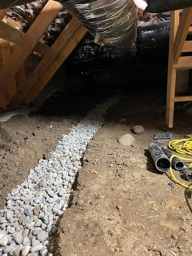 Gravel-filled drain line across the crawl space