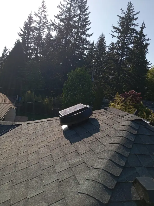 Low-profile solar attic fan near the roof ridge