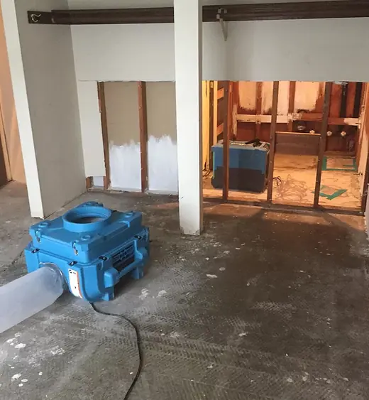 Air mover drying a room after wet drywall was cut out