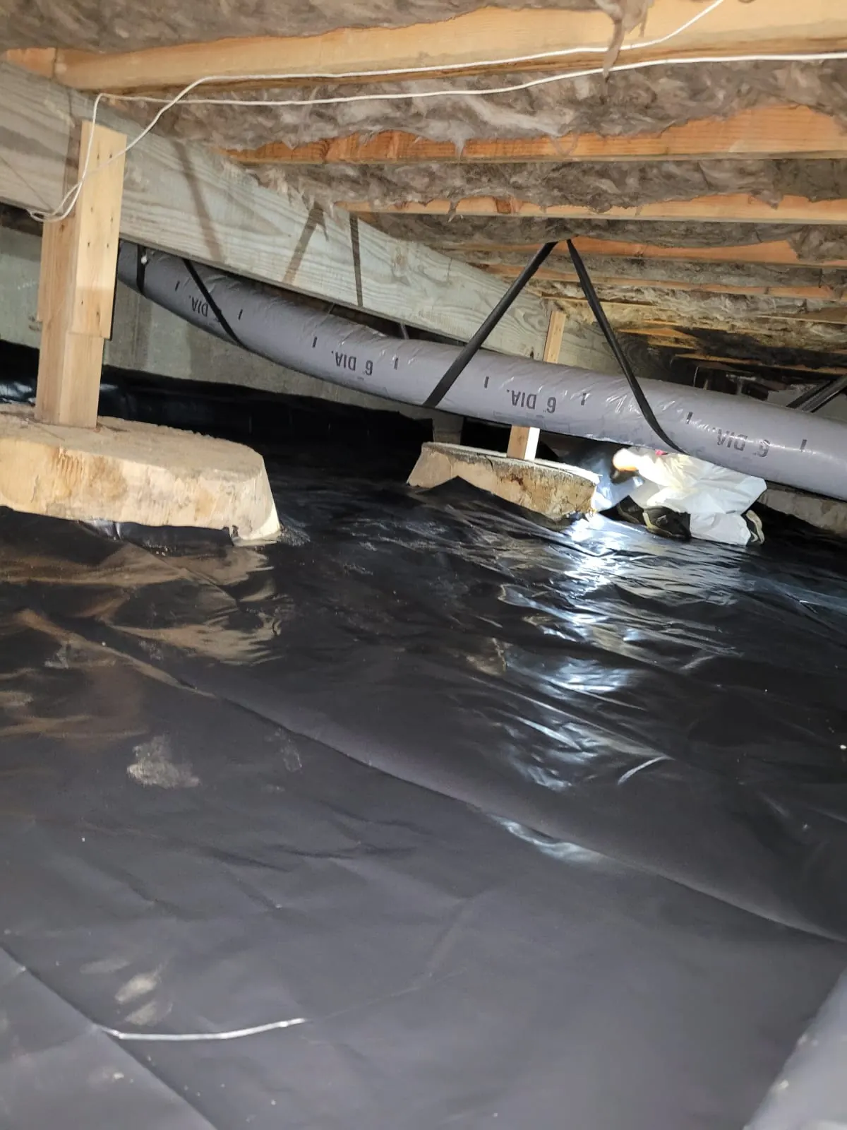New vapor barrier laid under ductwork in a crawl space