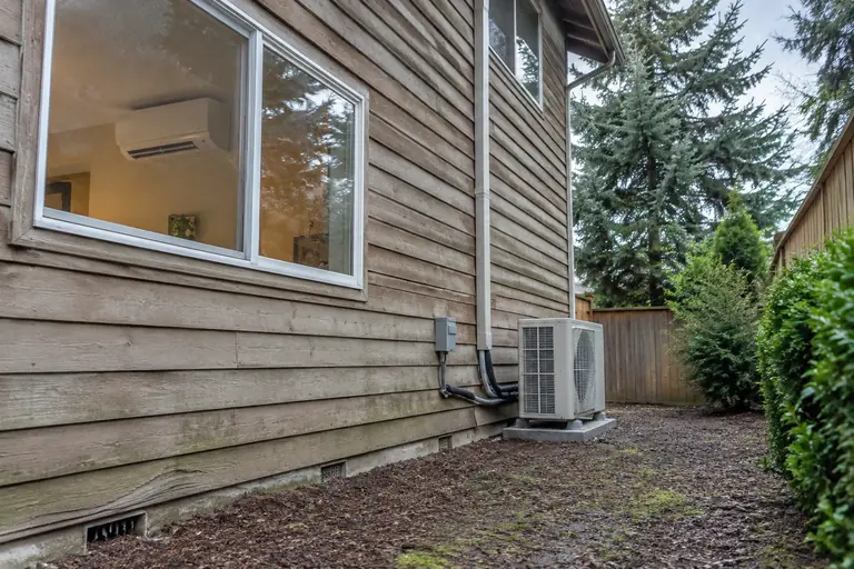 Ductless heat pump installed on a two-story home, after: Blending with the natural exterior, ready for Seattle's summer days.
