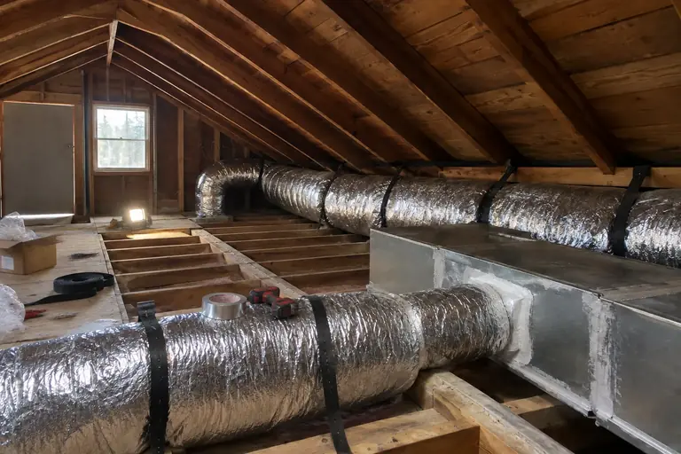 Air duct replacement in a Tacoma craftsman bungalow attic, in progress: A technician installs the new, insulated duct system.