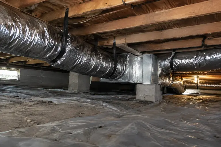 New insulated ducts hung in a crawl space.