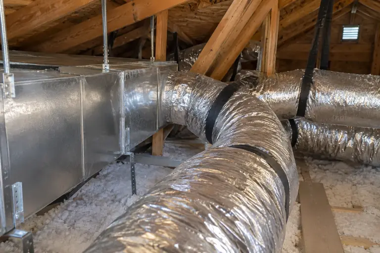 New insulated flexible ductwork and sealed sheet-metal trunk lines installed neatly in a clean attic space to enhance HVAC efficiency.