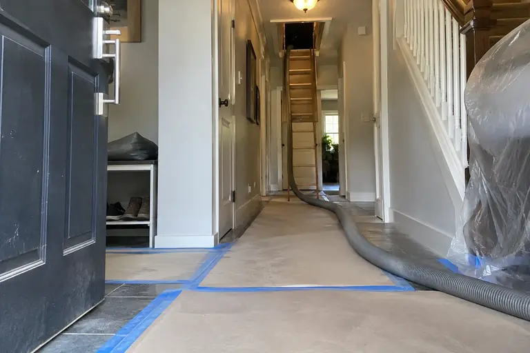 Protective floor coverings extend from the front door to the attic hatch inside a Seattle home.