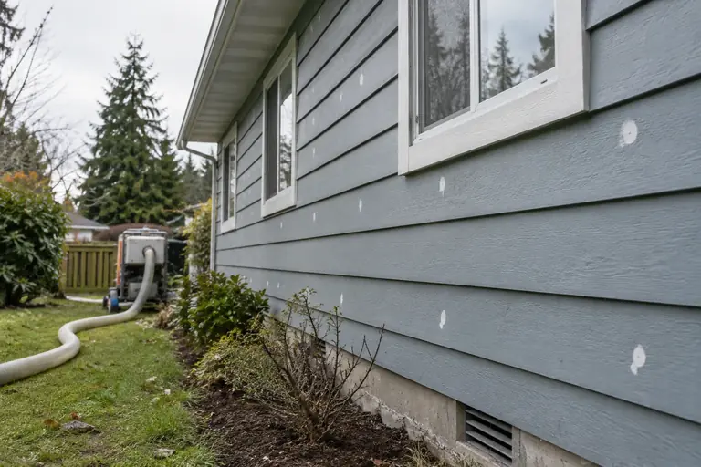 Wall insulation in progress, with the hose running from the machine.