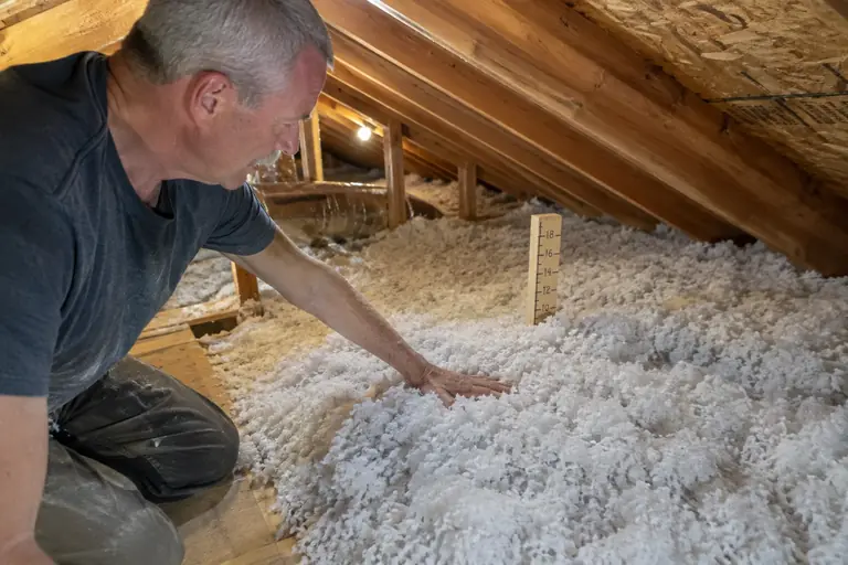 A technician applies fresh blown-in insulation in a Seattle Craftsman bungalow attic.