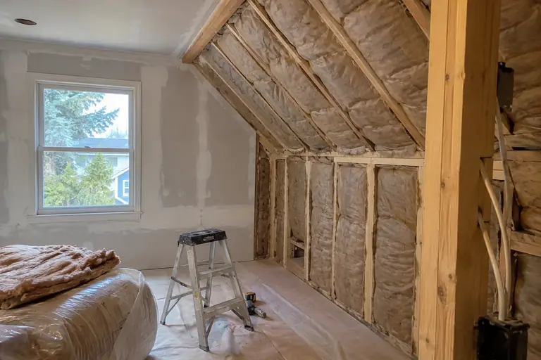 Insulation installed along a sloped ceiling in a finished attic room.
