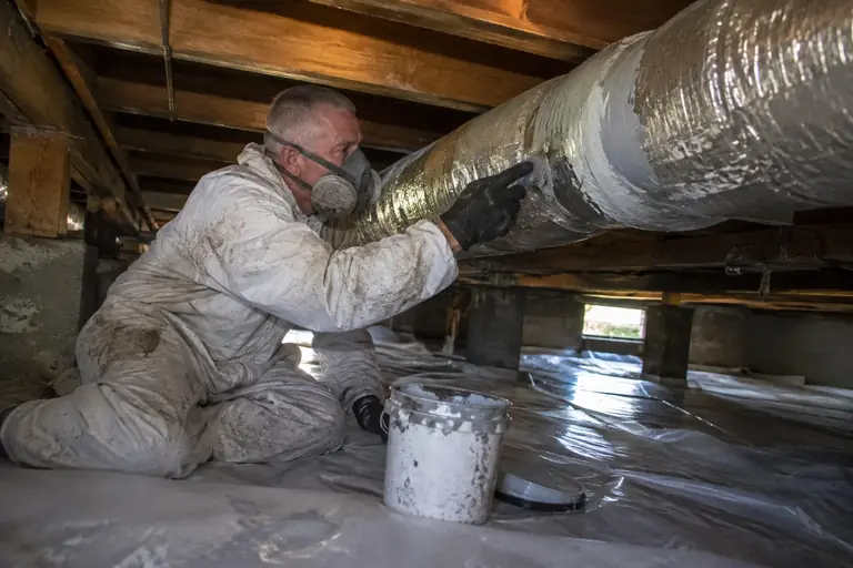 Technician sealing HVAC ducts with mastic.