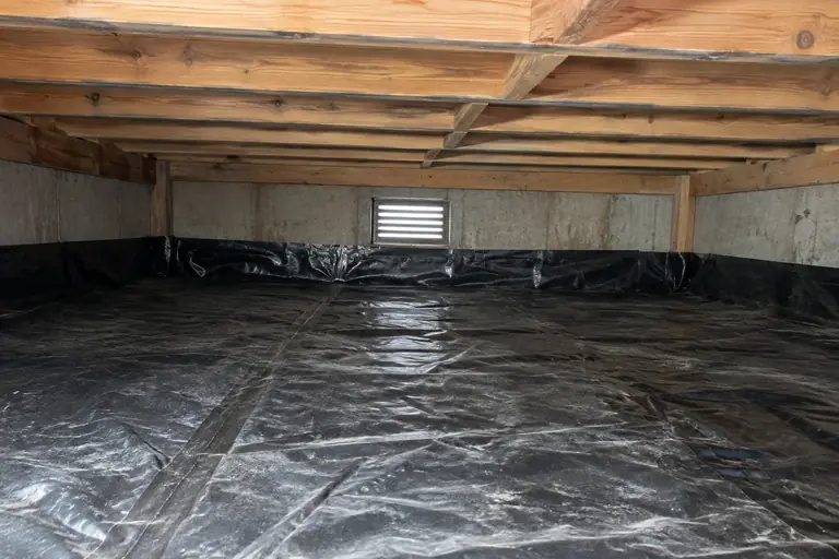 Crawl space cleaning with debris and insulation removal in Redmond split-level, after: Finished cleaning reveals a debris-free crawl space with a clean dirt floor and unobstructed vent, significantly.