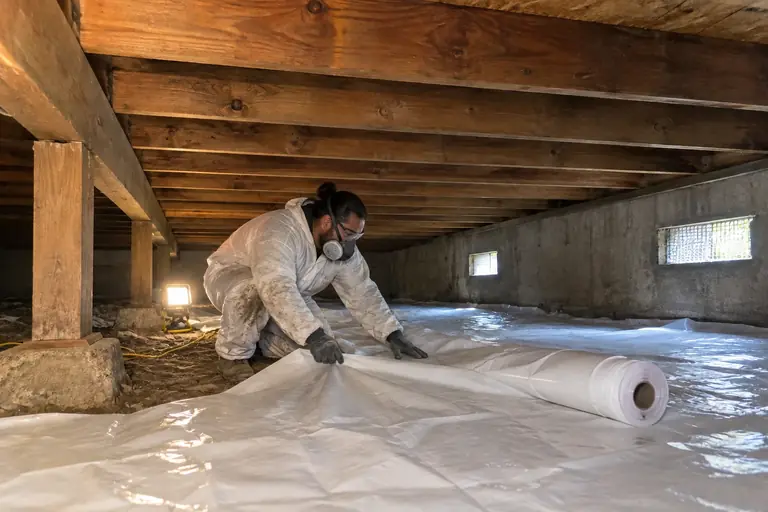 Crawl space cleaning with joist mold treatment, in progress: Technician carefully removes mold from the joists using hand tools.