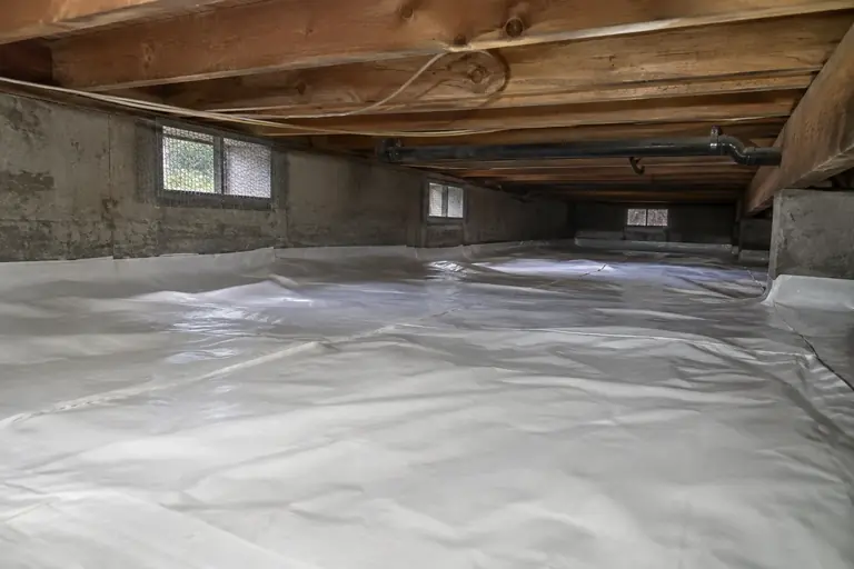 Crawl space cleaning with torn black poly removal and replacement, after: The crawl space is finished with a new white vapor barrier securely installed.
