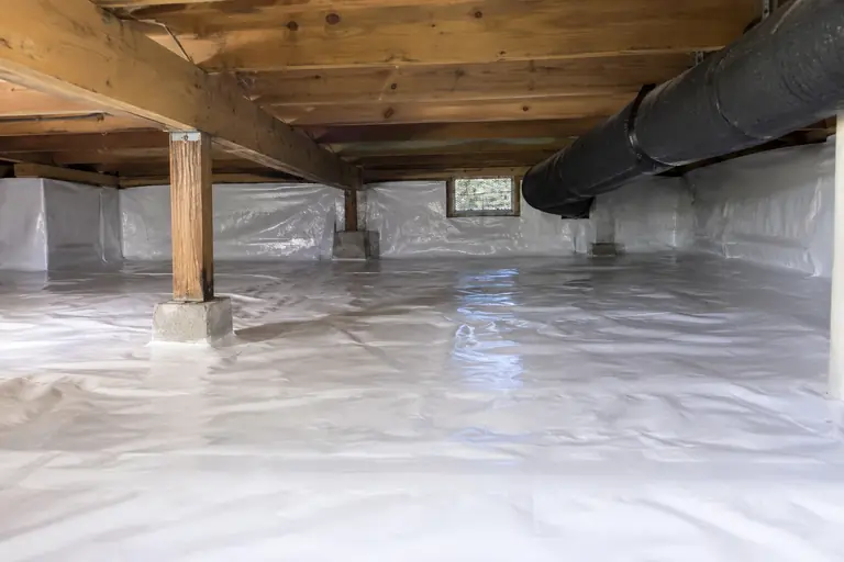 A crawl space sealed with a new white vapor barrier.