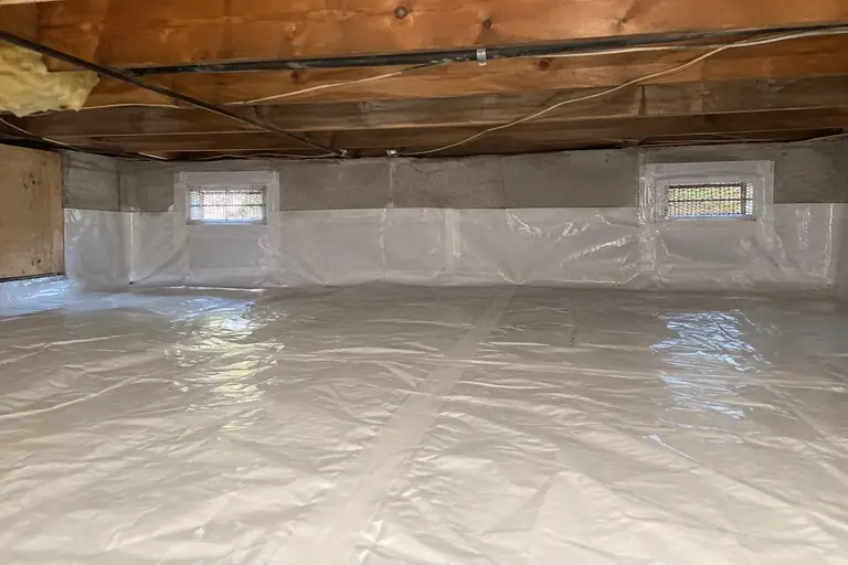 Moisture barriers in a vented crawl space on a mid-century rambler, after: The crawl space is now fully protected with a clean, sealed moisture barrier installed, eliminating all previous dampness and debris.