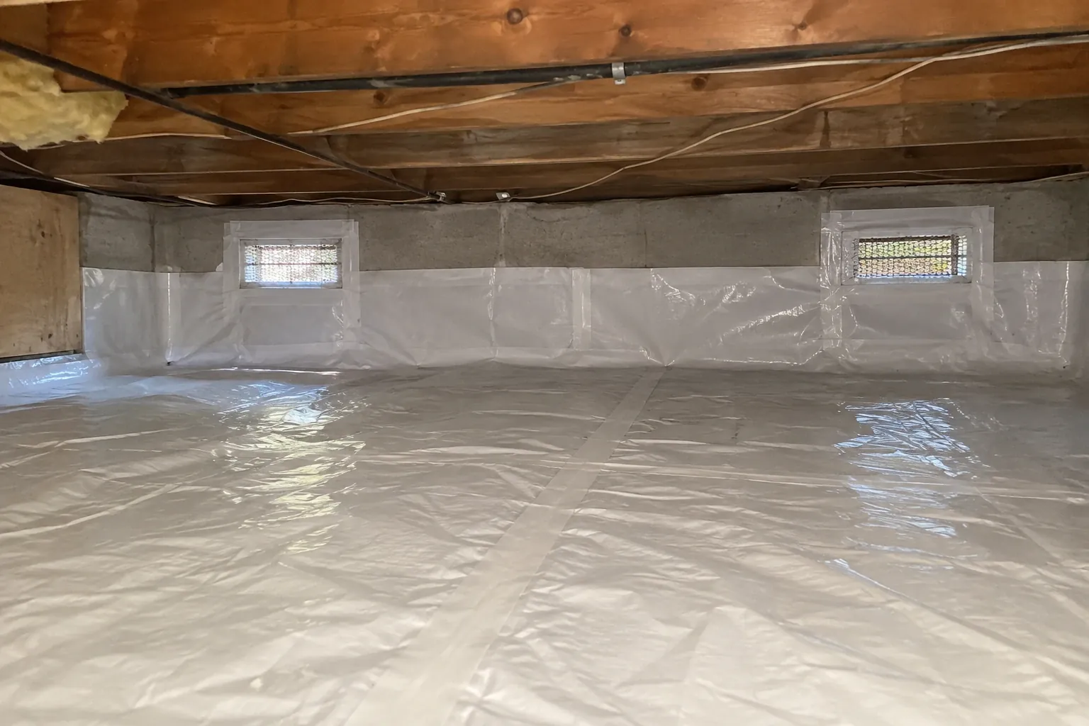 After: The crawl space is now fully protected with a clean, sealed moisture barrier installed, eliminating all previous dampness and debris.