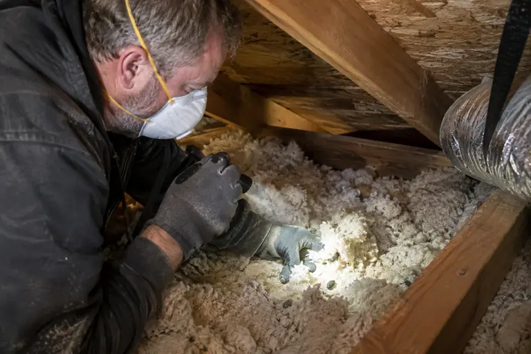 A technician inspects the attic insulation of a mid-century rambler.