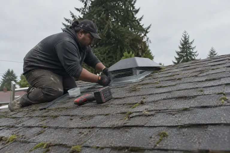 A technician seals a roof vent with steel mesh.
